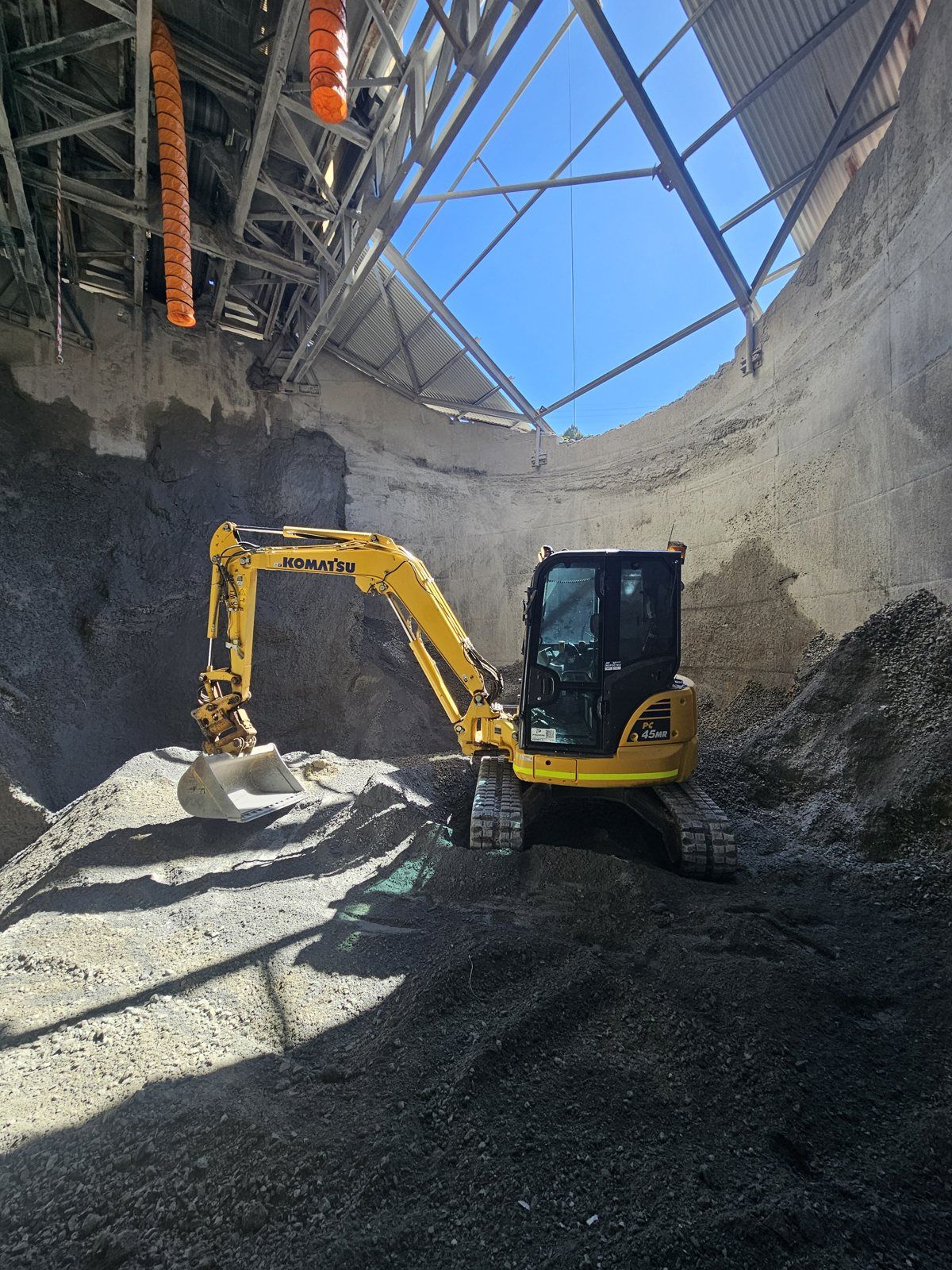 Excavator cleaning out a fine ore bin