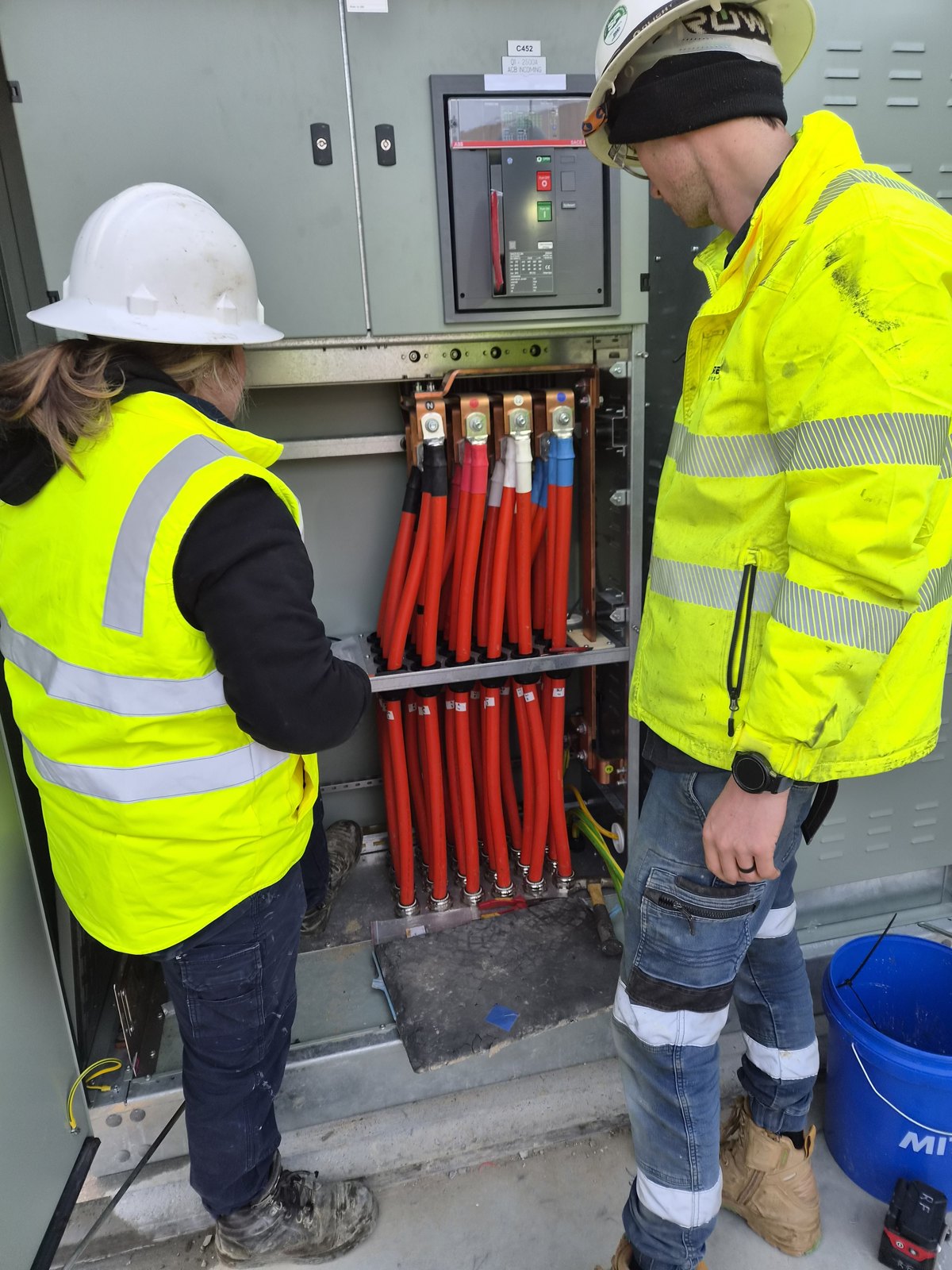 Electricians checking LV cable terminations on a main switchboard